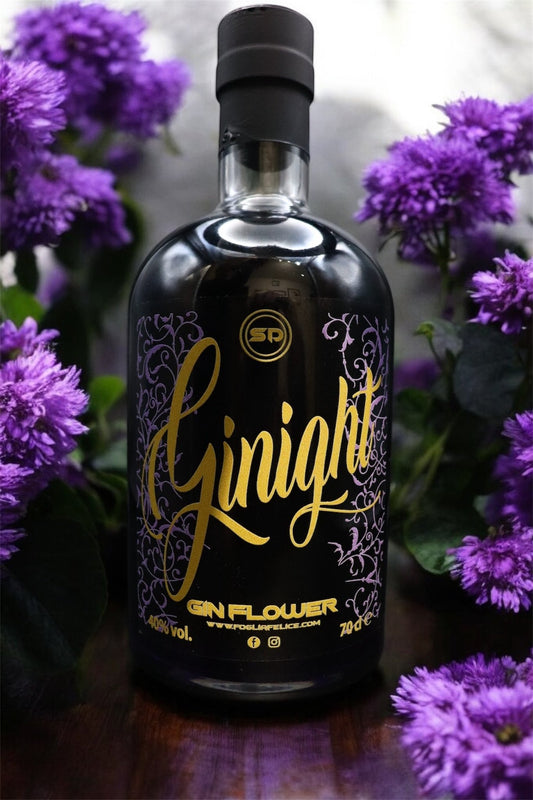 Bottle of Ginight gin surrounded by purple flowers, showcasing its unique black color and elegant design.